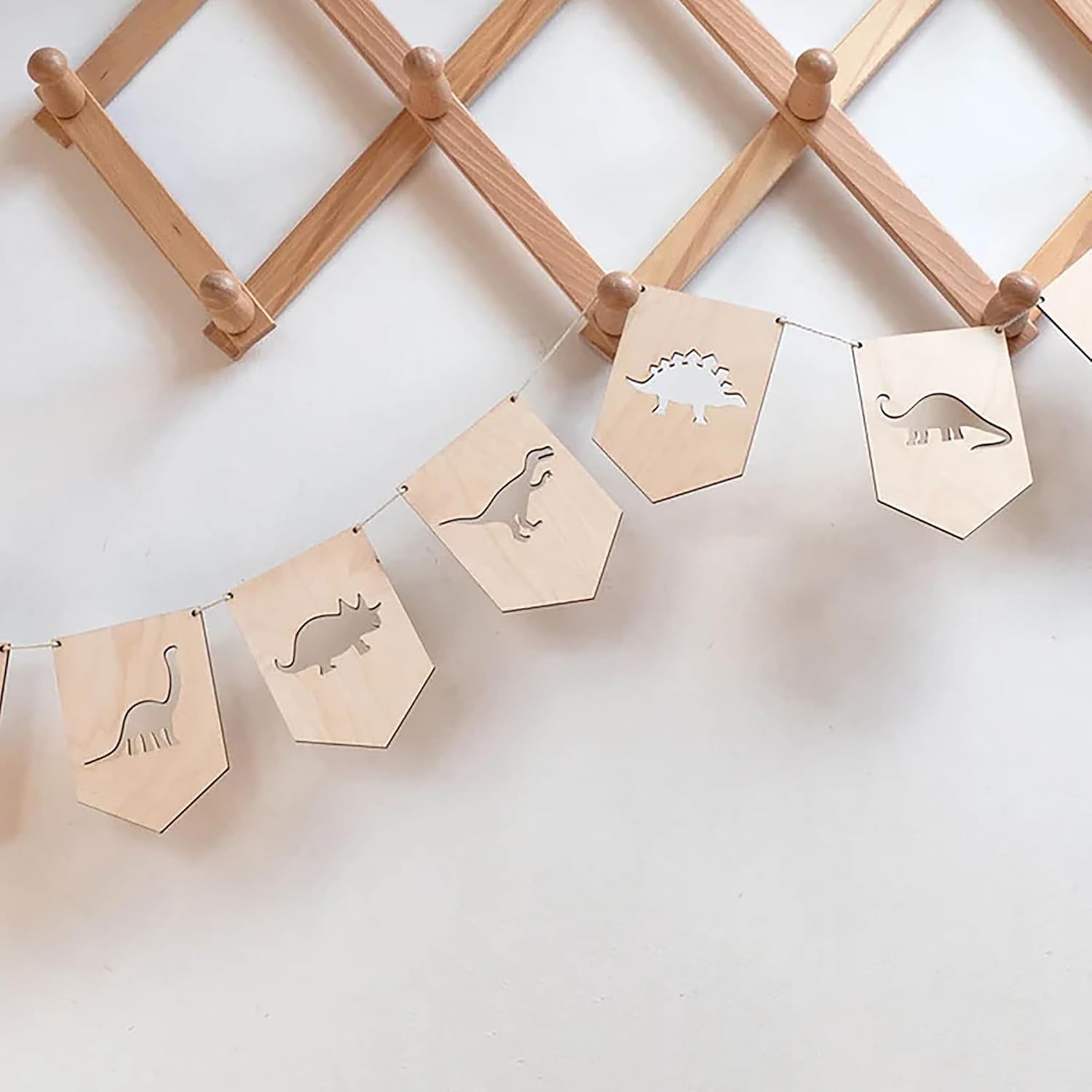 Wooden banner with dinosaur cutouts hanging on a wooden rack against a white wall.