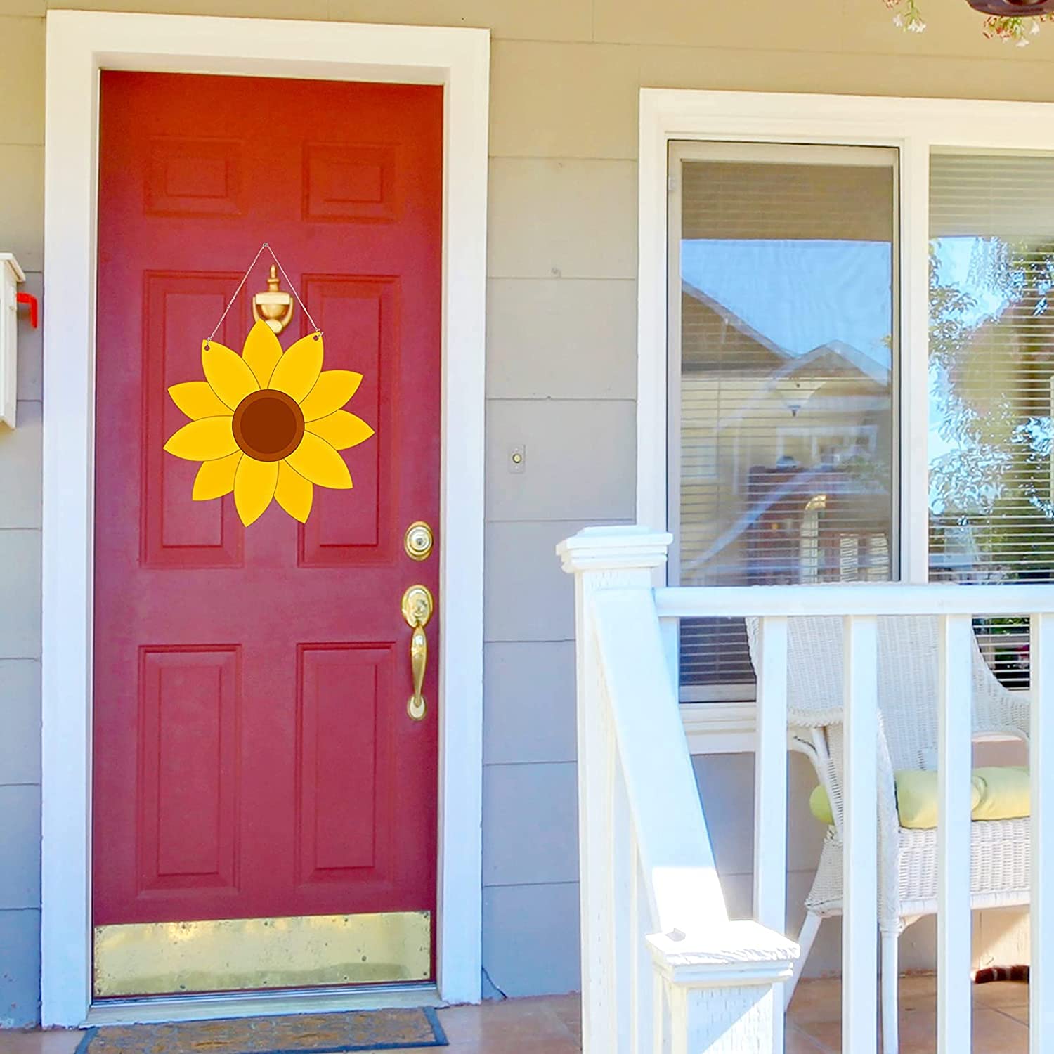 Red front door with a yellow sunflower wreath on a house exterior.