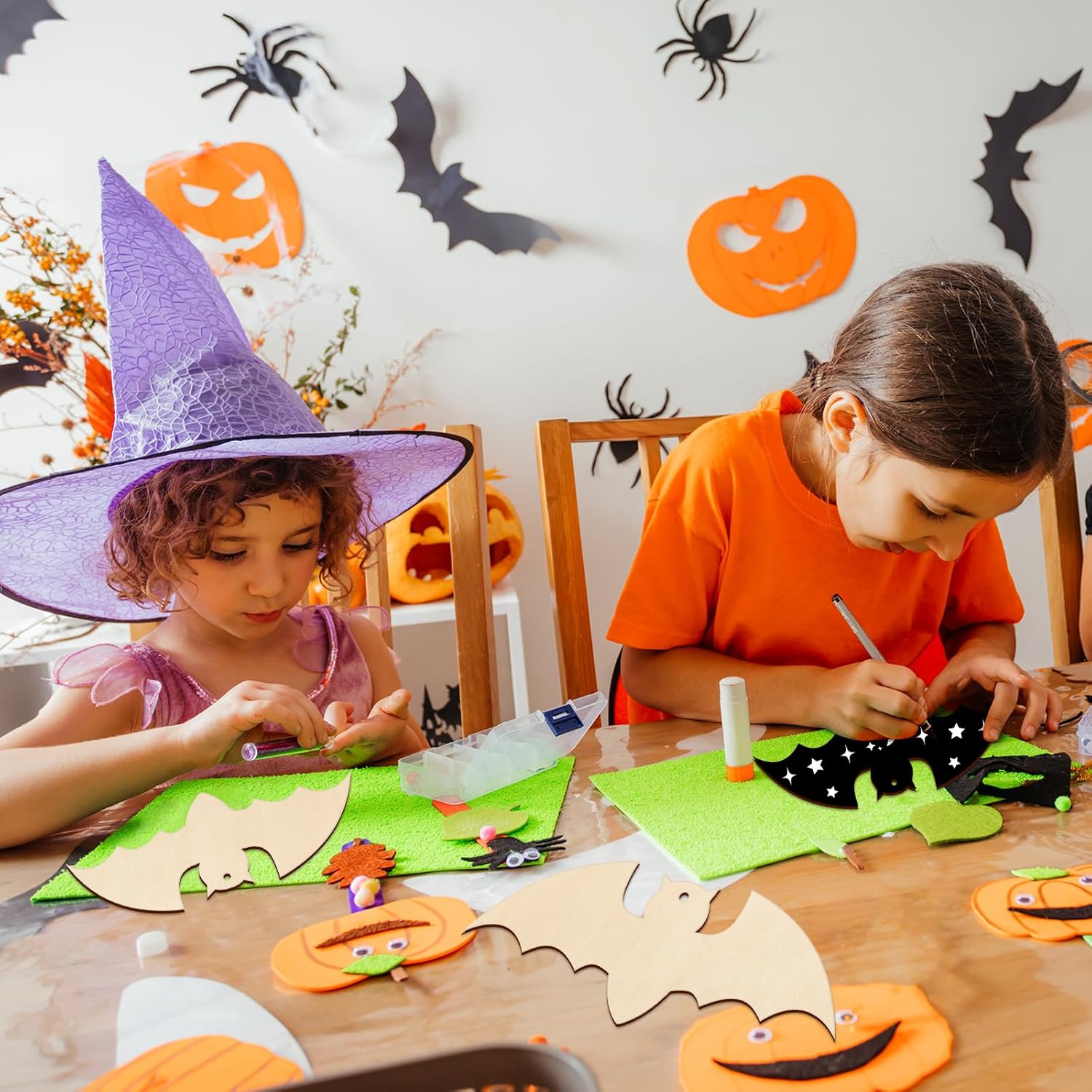 Two children engaged in Halloween-themed craft activities with decorative items on a table.