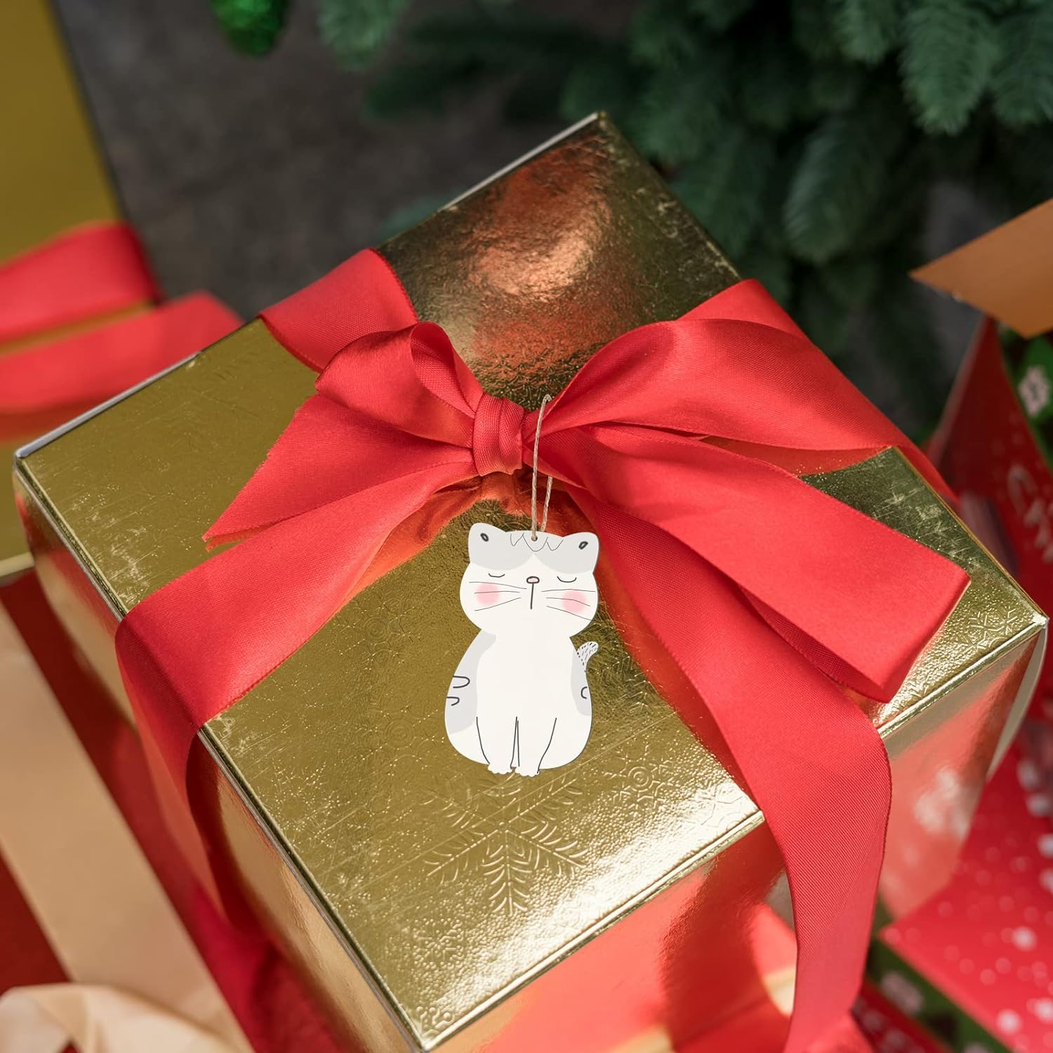 Gold gift box with a red ribbon and cat tag, surrounded by other wrapped presents.