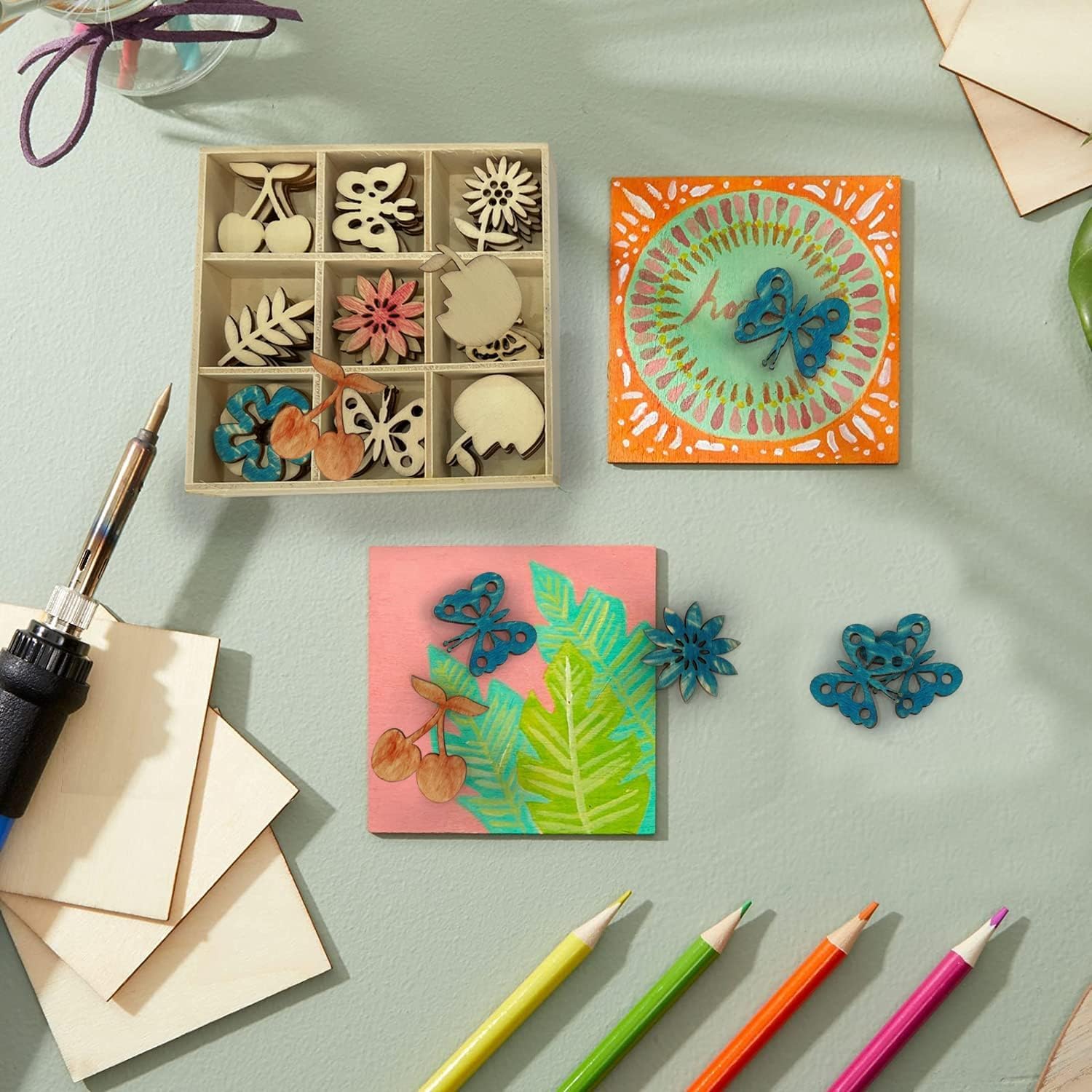 Crafting materials including wooden stamps, colored pencils, and decorative items on a light green surface.