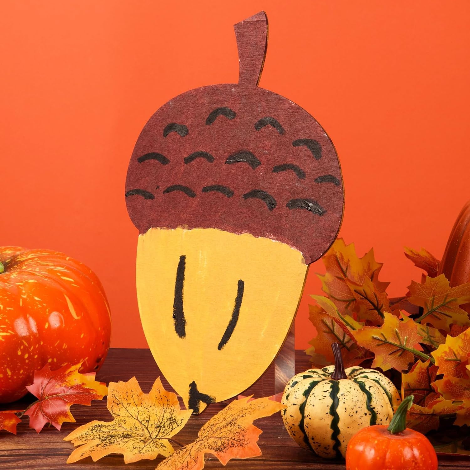 Decorative acorn with pumpkins and leaves on an orange background