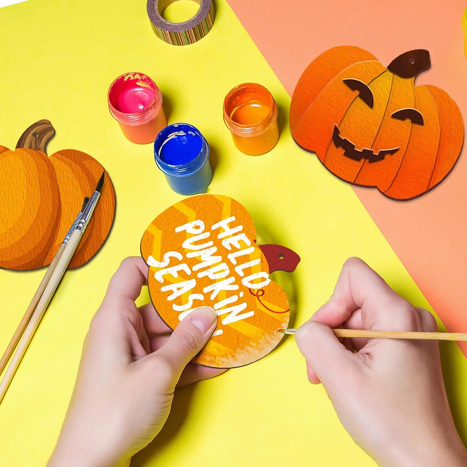 Person decorating a paper pumpkin with 'Hello Pumpkin Season' text on a colorful background.