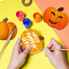 Person decorating a paper pumpkin with 'Hello Pumpkin Season' text on a colorful background.