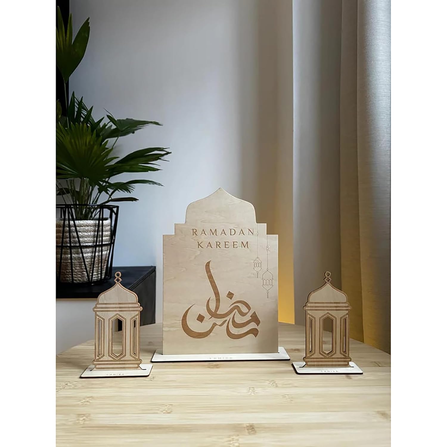 Decorative set with 'Ramadan Kareem' sign and lanterns on a wooden surface.