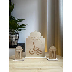 Decorative set with 'Ramadan Kareem' sign and lanterns on a wooden surface.