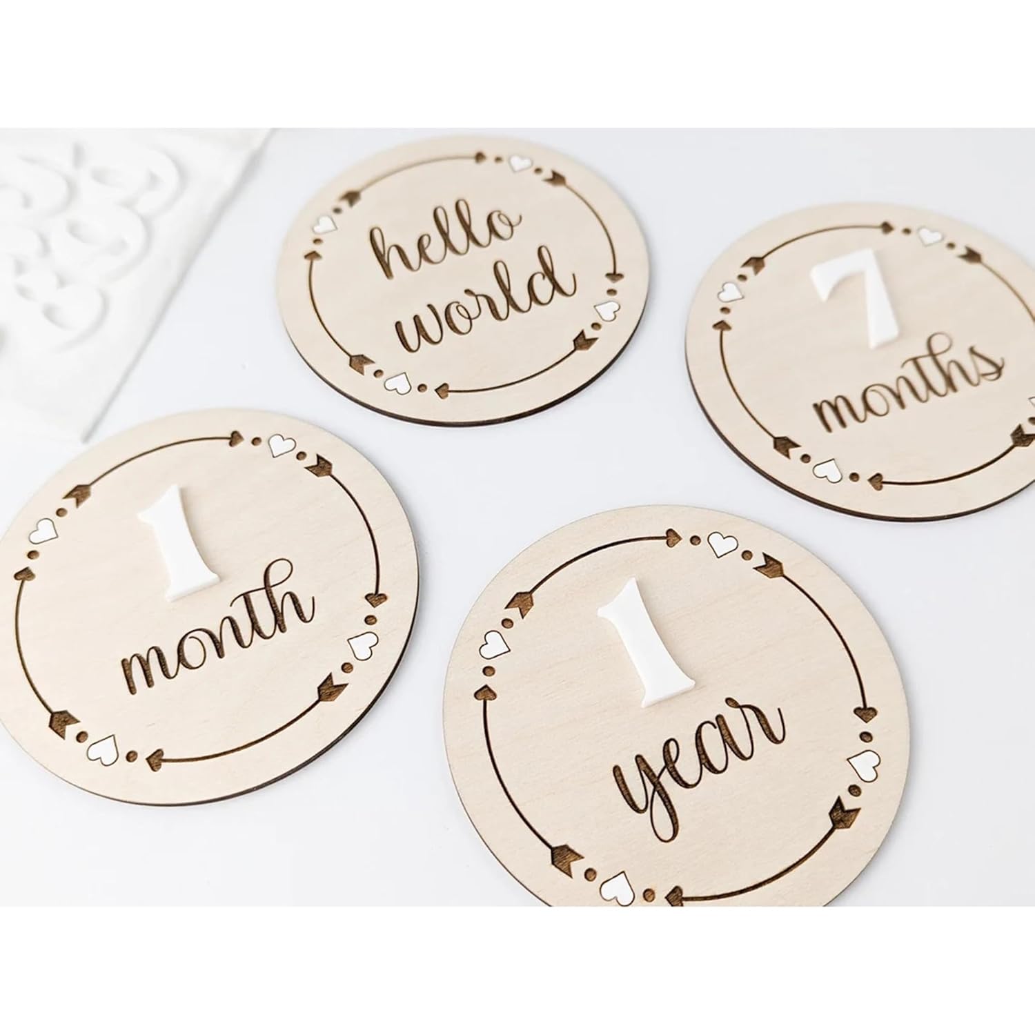 Wooden milestone discs with text for baby's first year on a white background