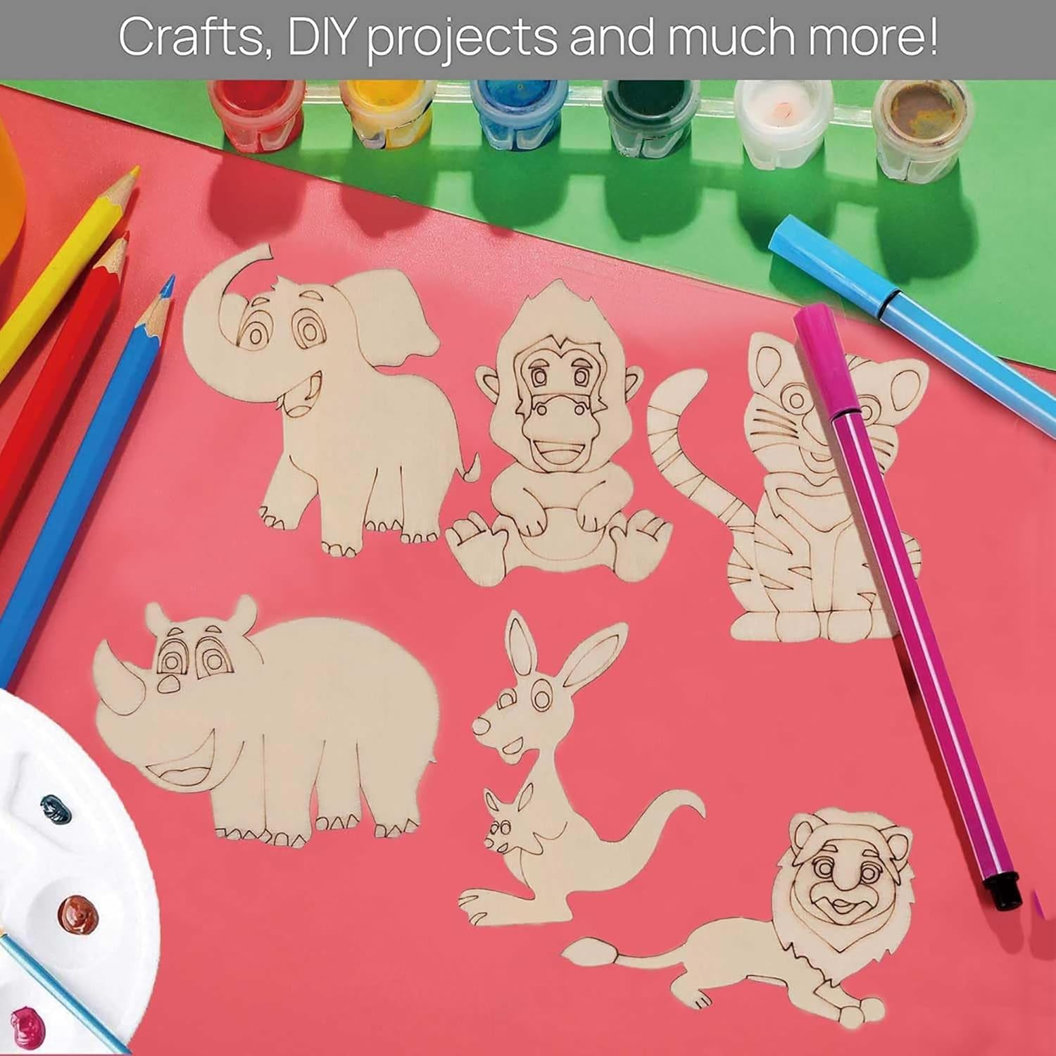 Colorful animal cutouts on a pink sheet with art supplies on a green surface.
