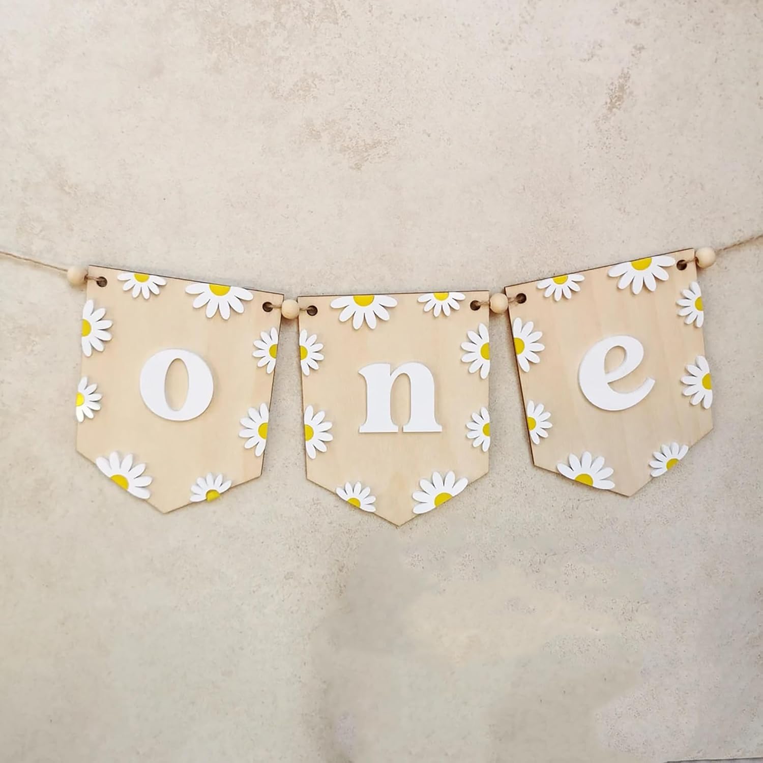Decorative banner with 'one' surrounded by daisy flowers on a beige background