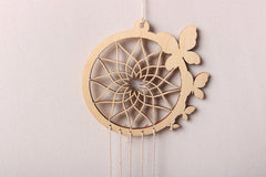 Wooden dreamcatcher with feathers on a light gray background