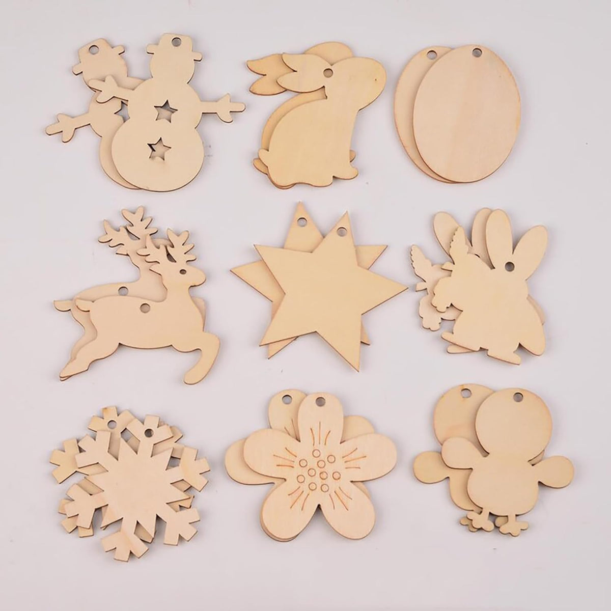 Set of wooden Christmas ornaments including snowflakes, stars, and animals on a light gray background.