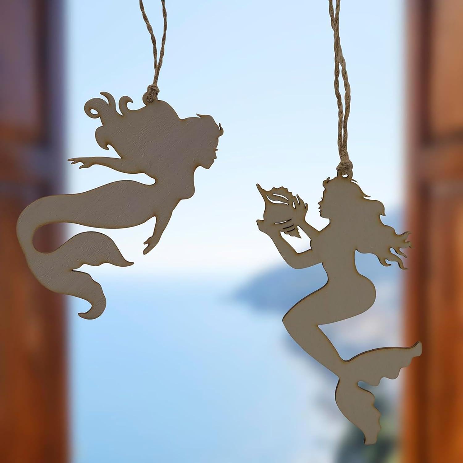 Two mermaid-shaped decorations hanging against a blurred background