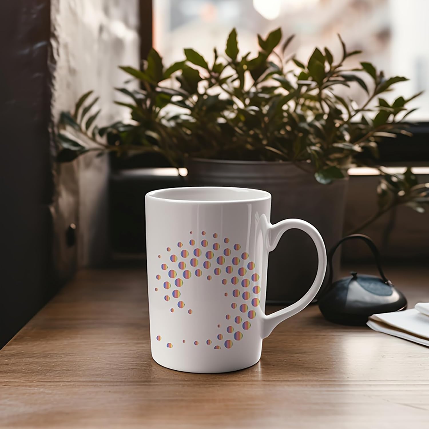 White mug with colorful dots on a wooden surface with a plant in the background
