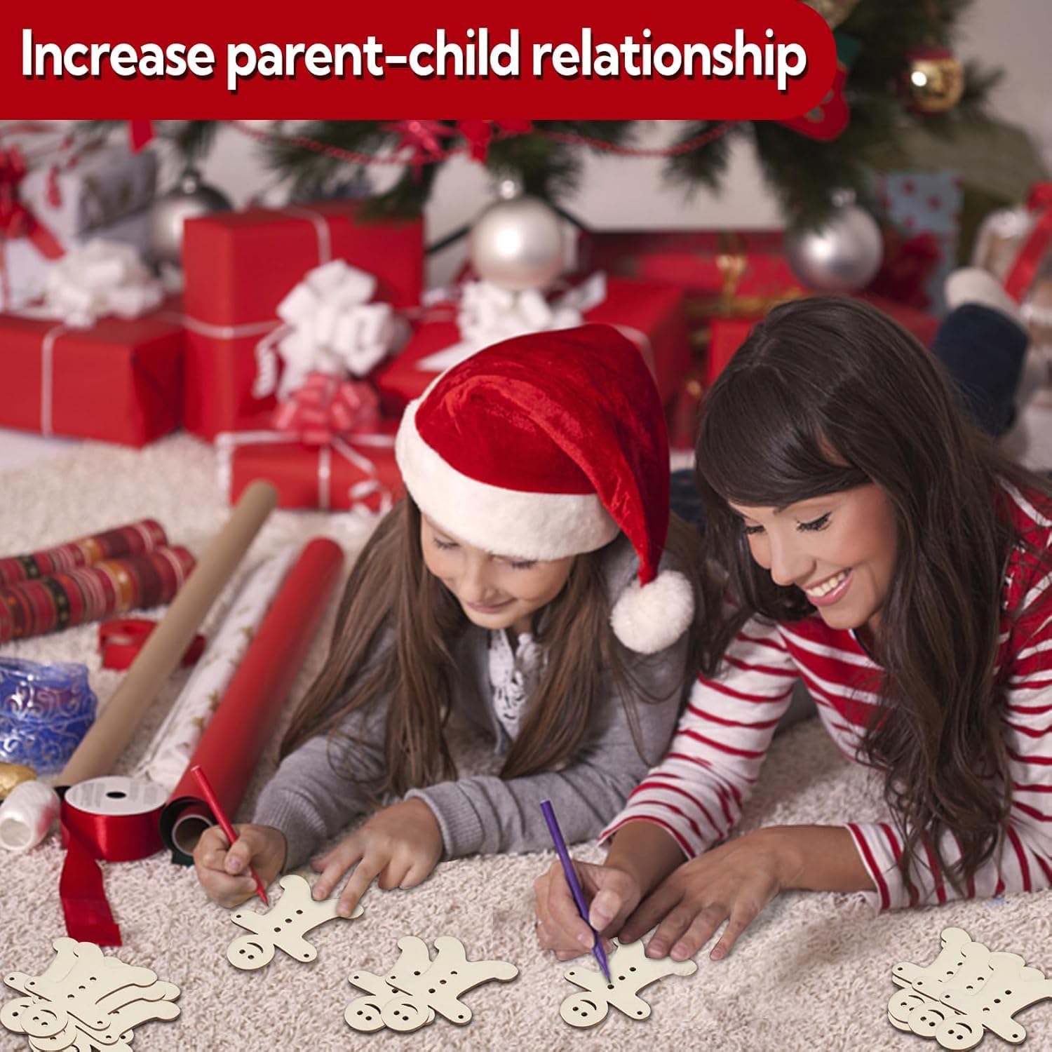 Two children decorating wooden snowflakes in front of a Christmas tree with presents.