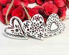 Three decorative heart shapes with intricate patterns on a white surface with red floral background