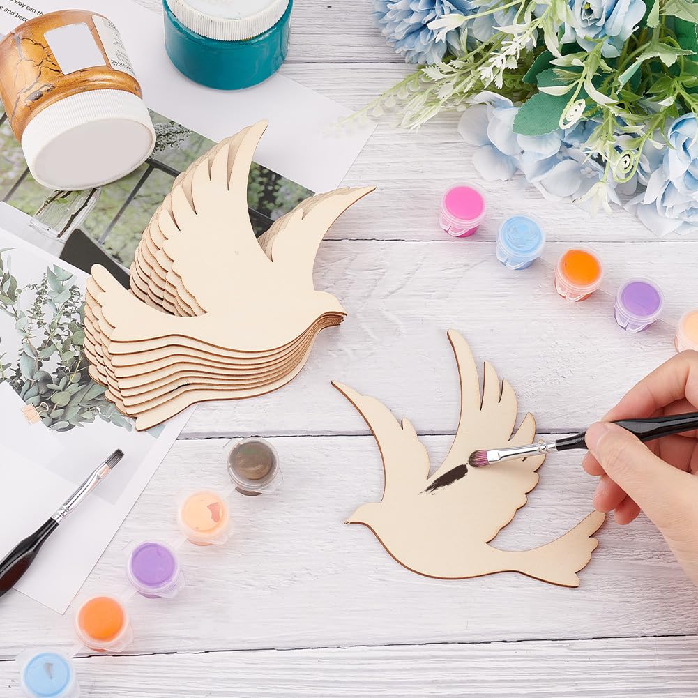 Person painting wooden bird shapes on a table with paint bottles and brushes.