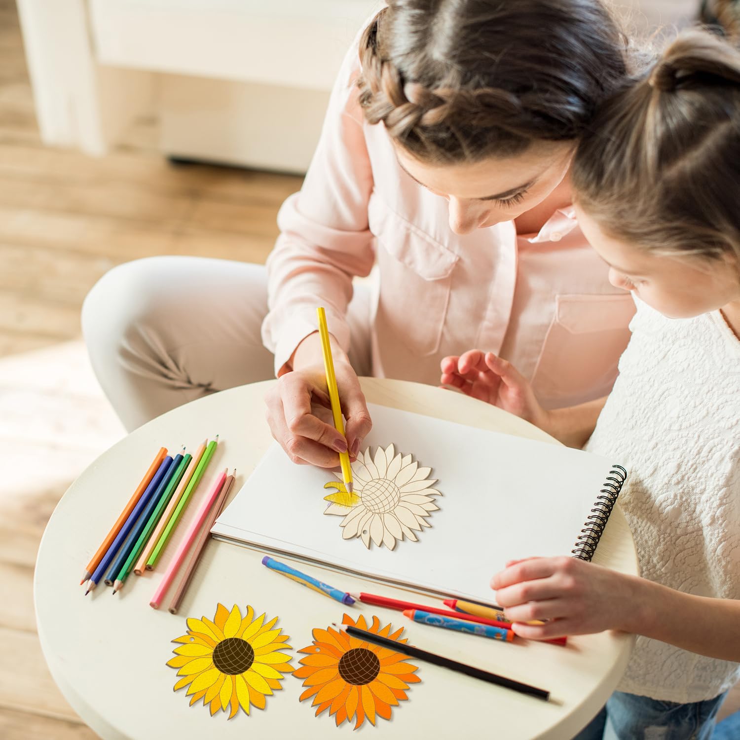 Two children drawing with colored pencils on a table.