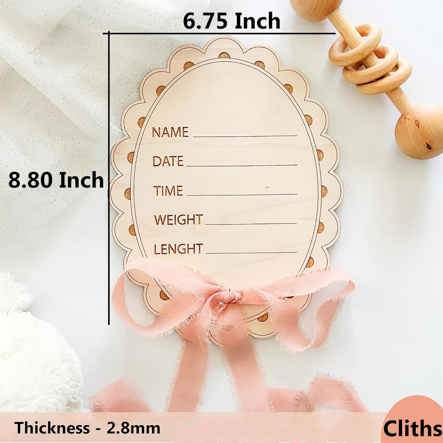 Wooden baby milestone card with measurements and text space, accompanied by a pink ribbon and wooden rattle.