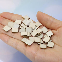 Hand holding a small pile of wooden square pieces against a light blue background