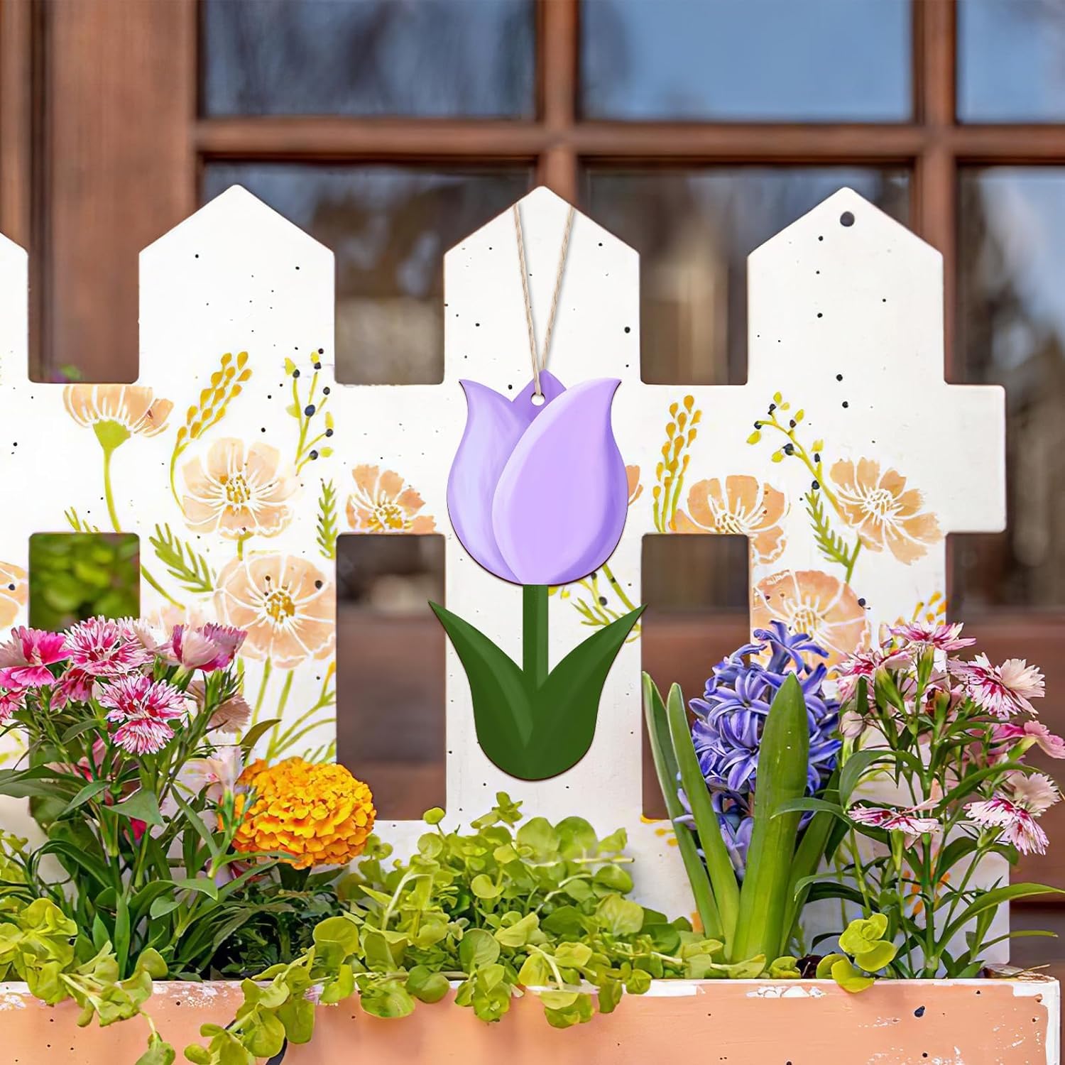 Decorative garden scene with a white picket fence, flowers, and plants.