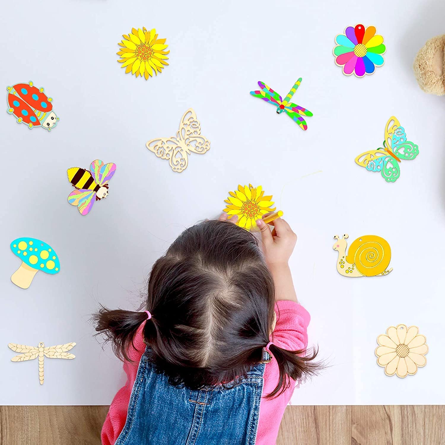 Child playing with colorful wooden stickers on a white surface