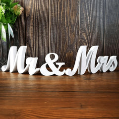 White 'Mr & Mrs' sign on a wooden surface with a wooden background