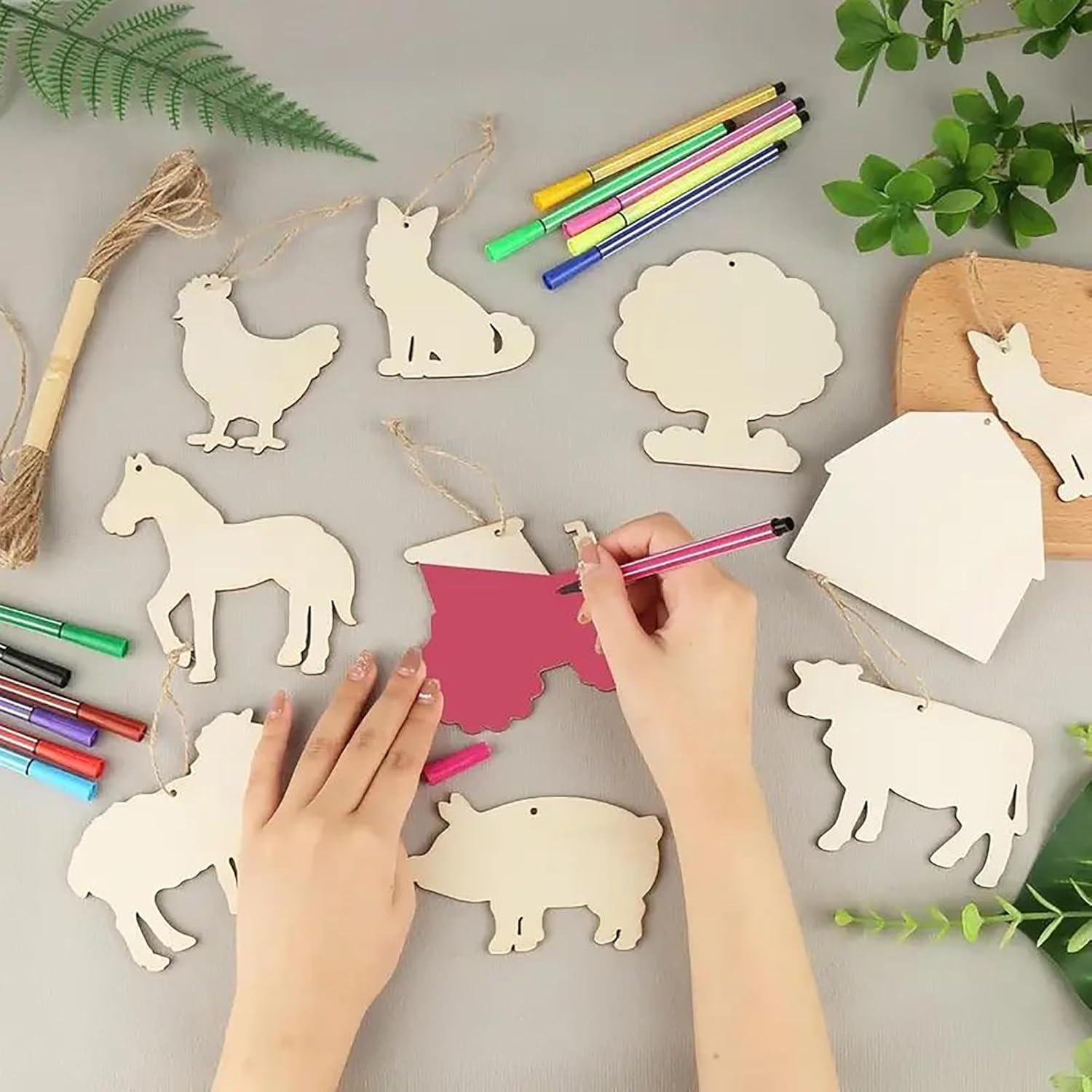 Children's hands coloring wooden animal cutouts on a gray surface with markers.