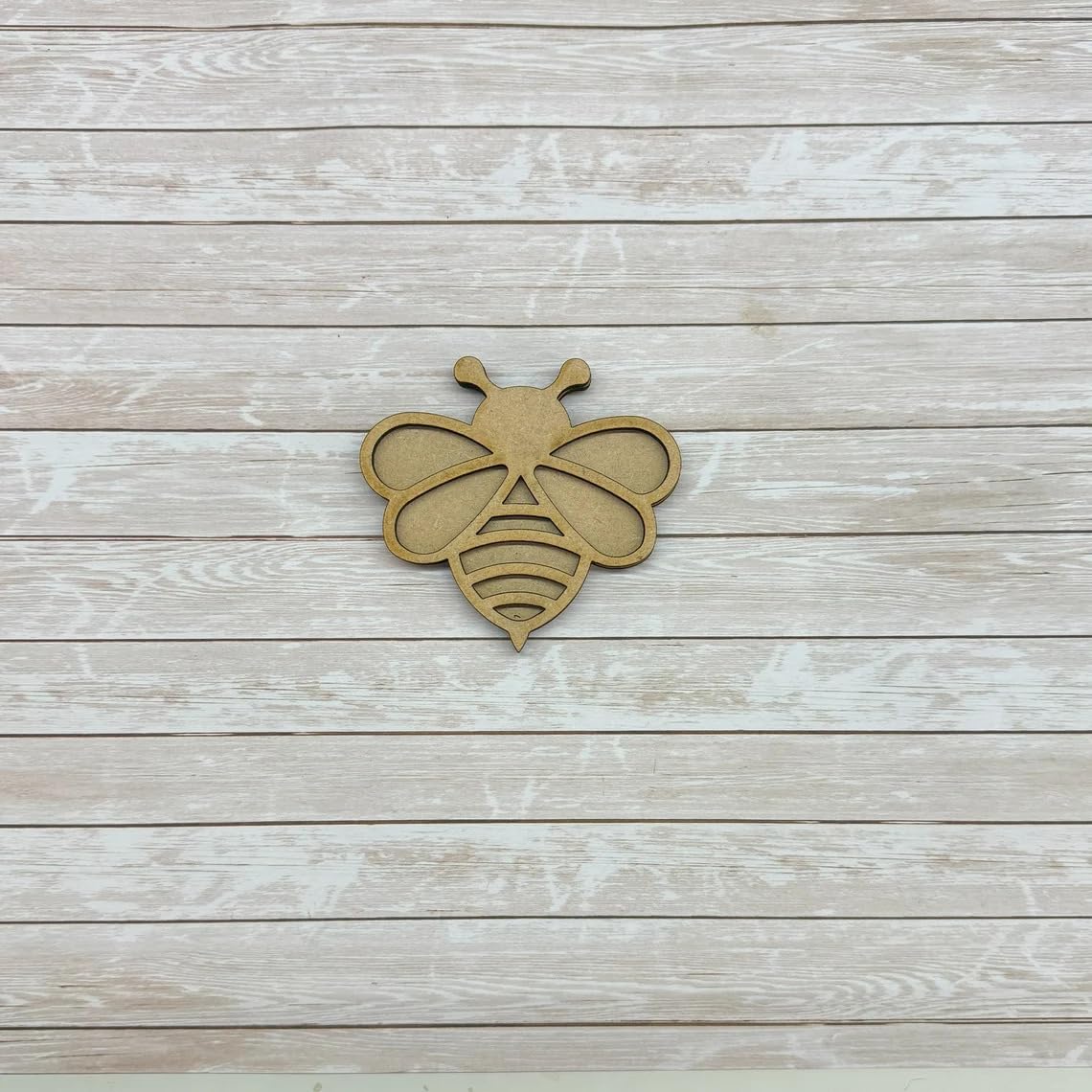 Wooden bee-shaped cutout on a wooden surface