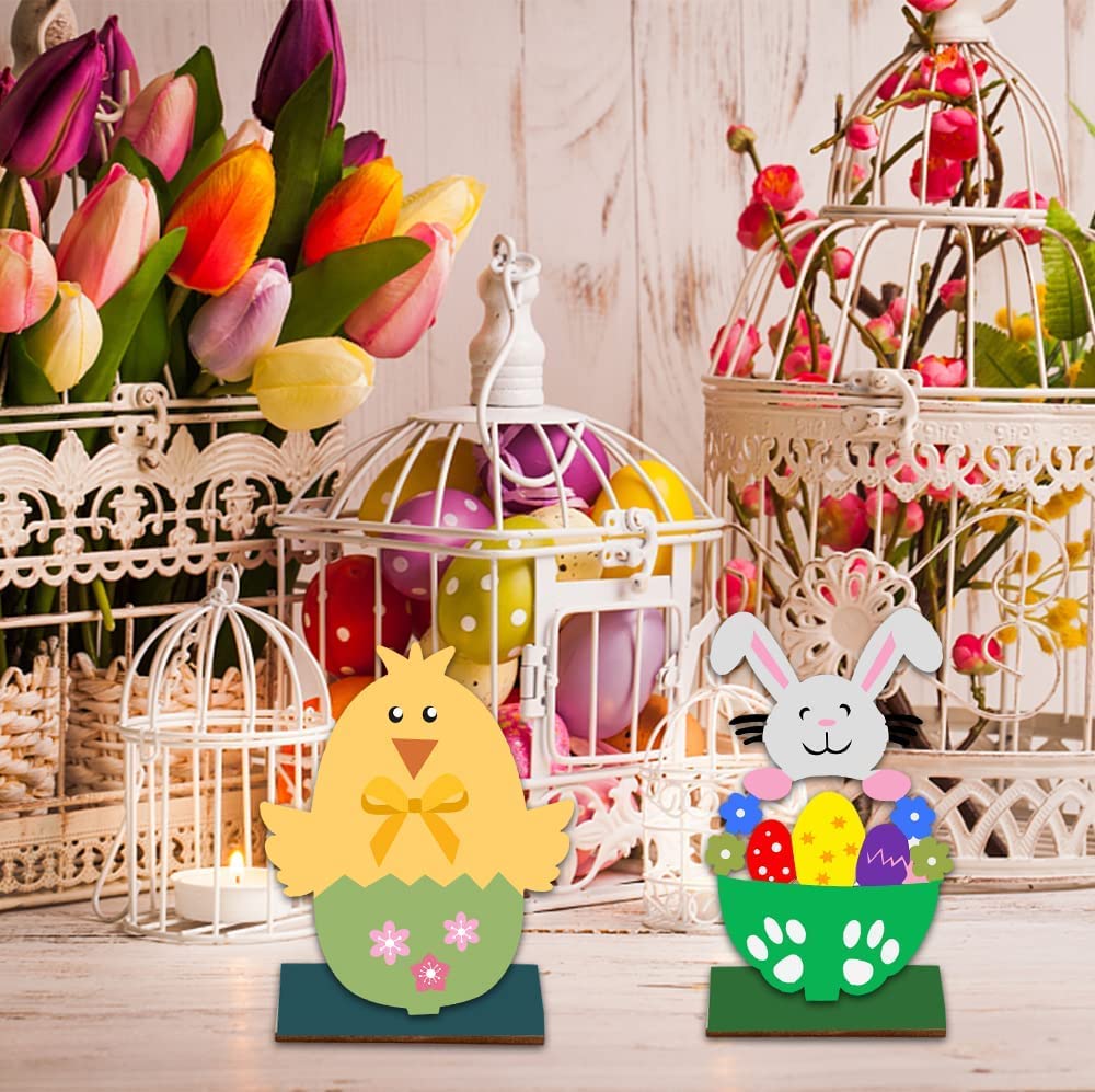 Decorative Easter items including a chick, bunny, and eggs with flowers in cages on a wooden background.