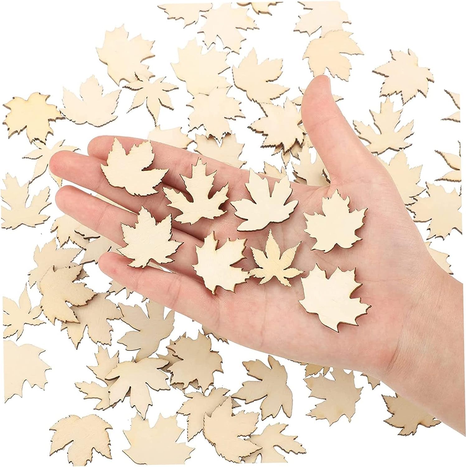 Hand holding wooden leaf cutouts with a background of more leaf cutouts