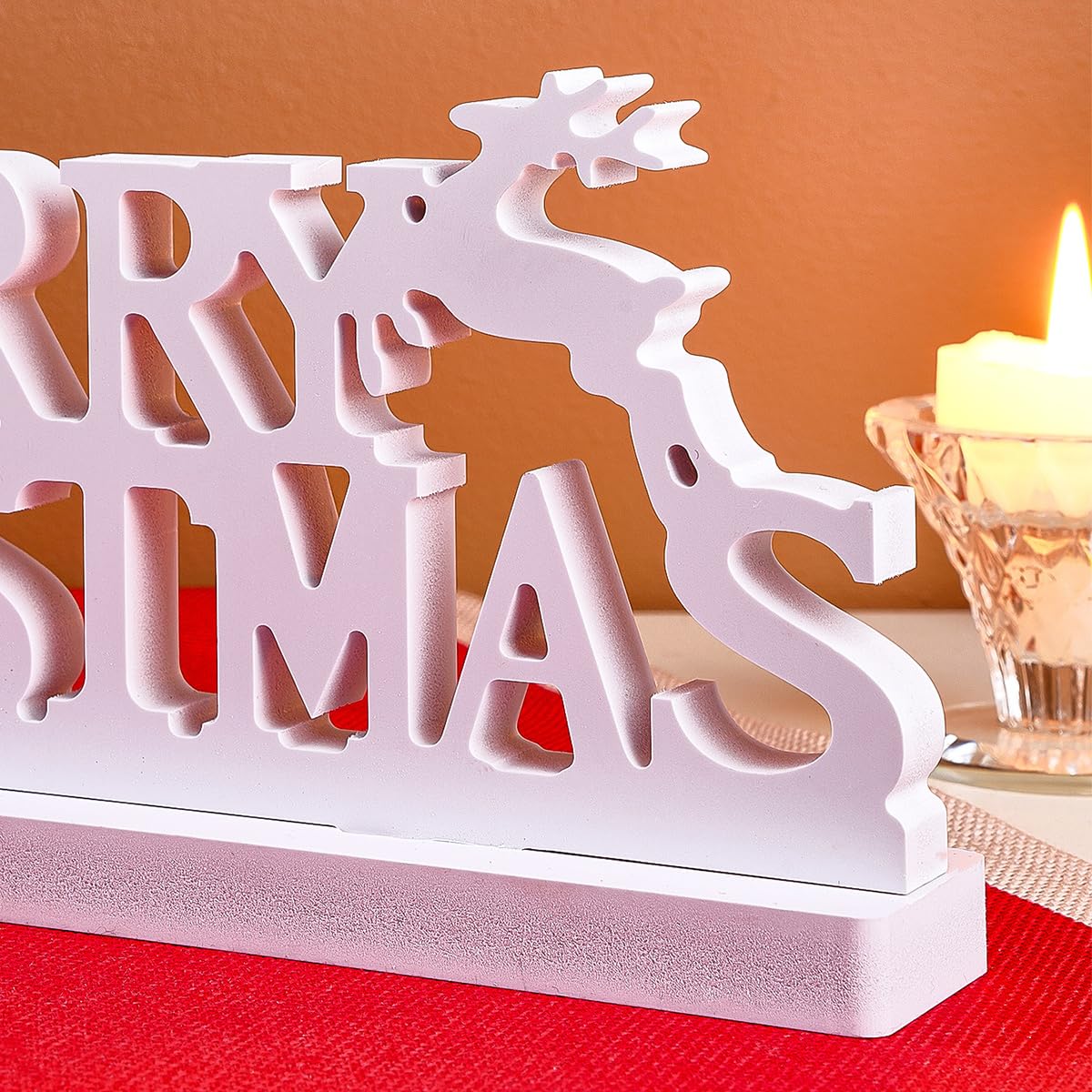 Decorative Christmas sign with reindeer and 'Merry Christmas' text on a red surface.