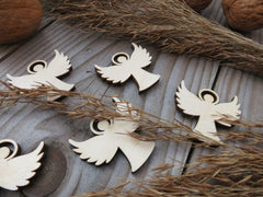 Wooden angel ornaments on a rustic wooden surface with twigs and nuts.