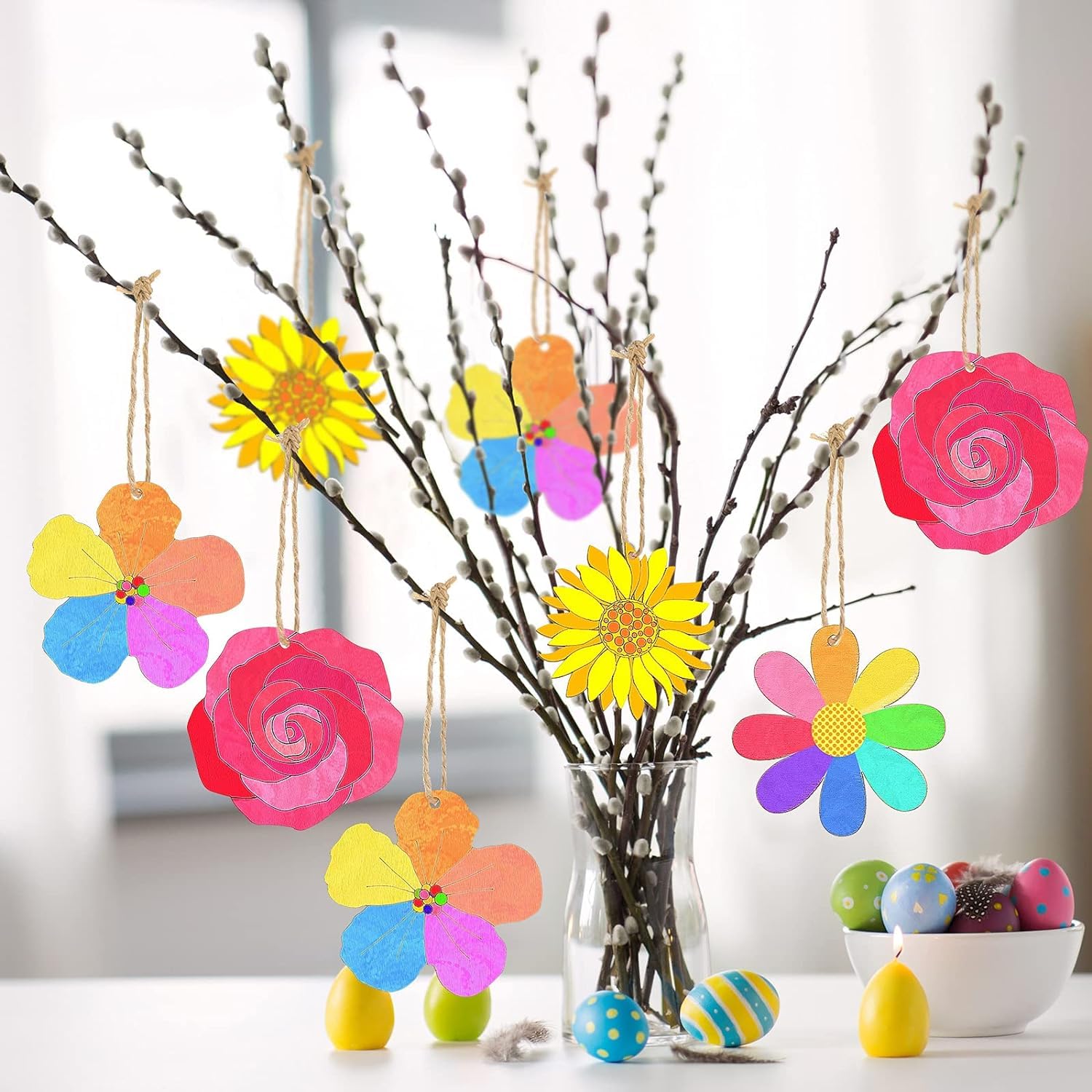 Colorful paper flowers hanging from branches with a blurred background