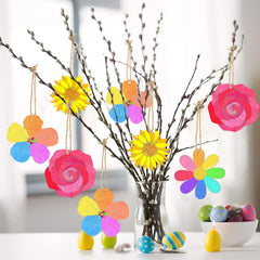 Colorful paper flowers hanging from branches with a blurred background