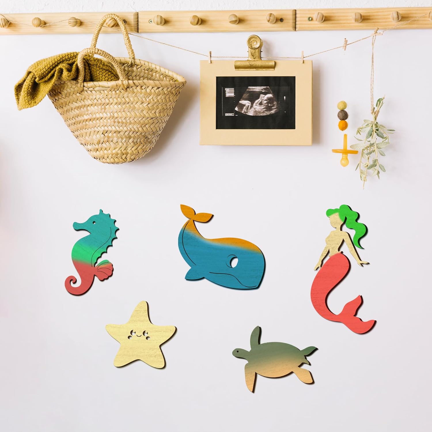 Colorful wooden sea-themed wall hooks on a white wall with a basket and ultrasound photo in the background.