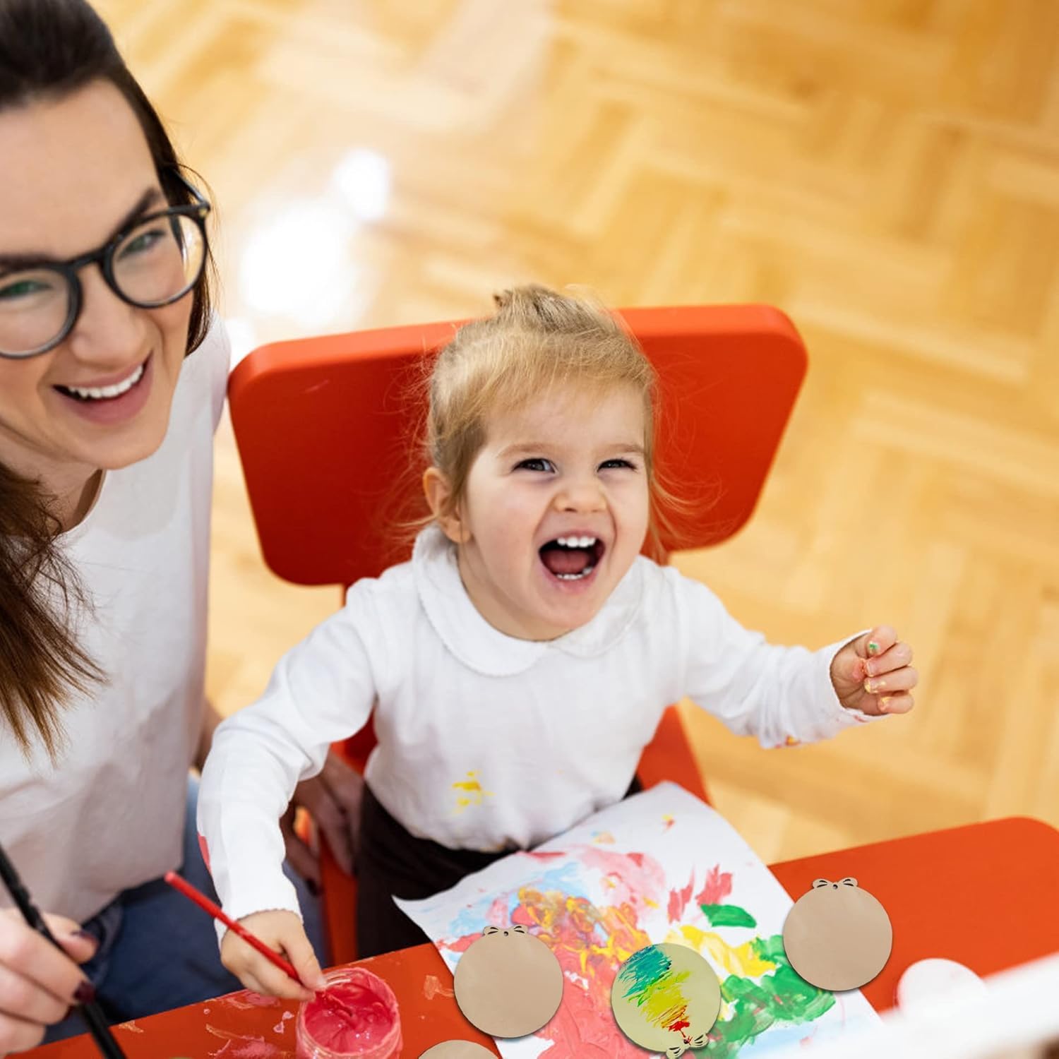 Woman and child sitting at a table with art supplies, smiling.
