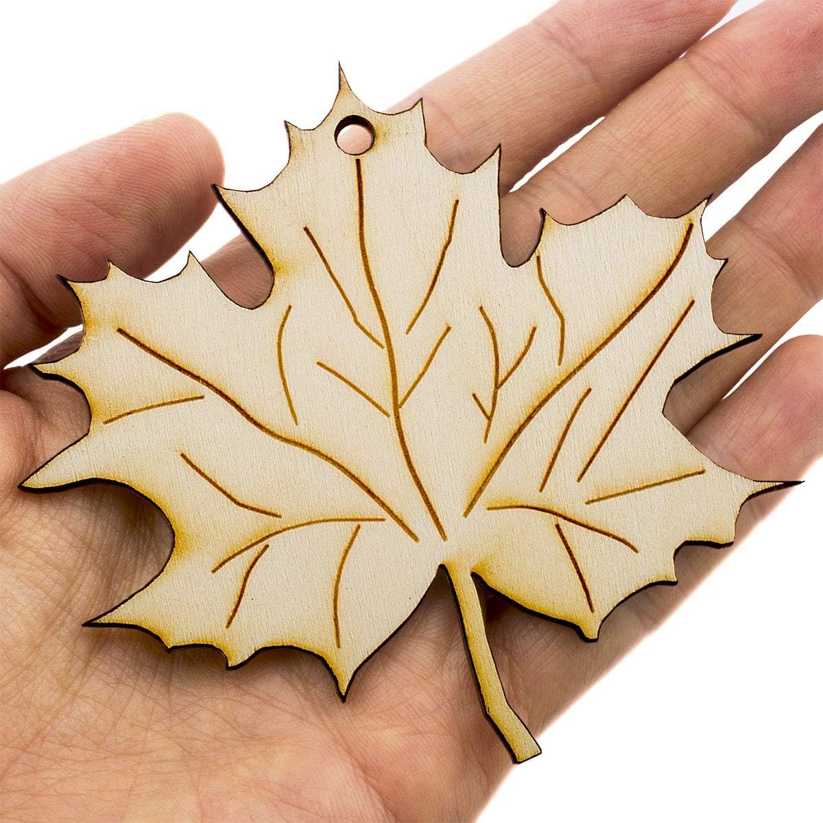 Hand holding a leaf-shaped wooden ornament with a white background