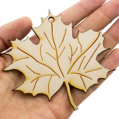 Hand holding a leaf-shaped wooden ornament with a white background