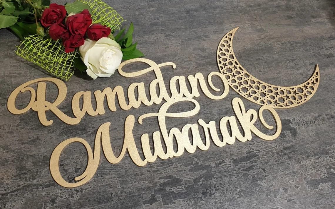 Wooden 'Ramadan Mubarak' sign with a decorative crescent moon on a gray surface with flowers.