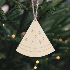 Wooden Christmas ornament shaped like a triangle with cut-out patterns, hanging on a tree.