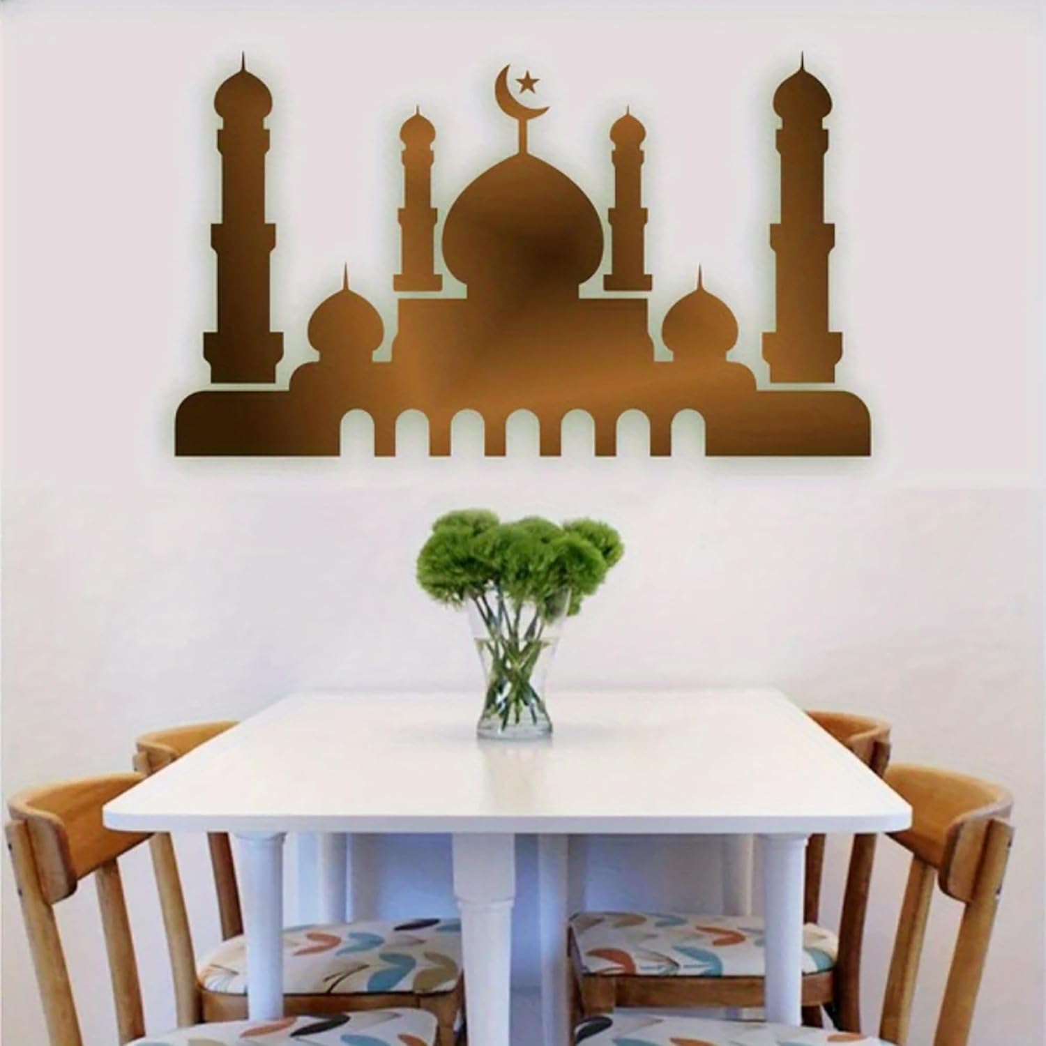 Decorative wall art of a mosque silhouette above a dining table with chairs.