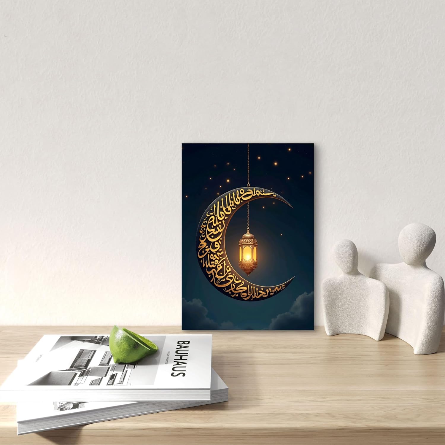 Decorative wall art with a crescent moon and Arabic calligraphy on a dark blue background, placed on a wooden surface with a magazine and decorative items.