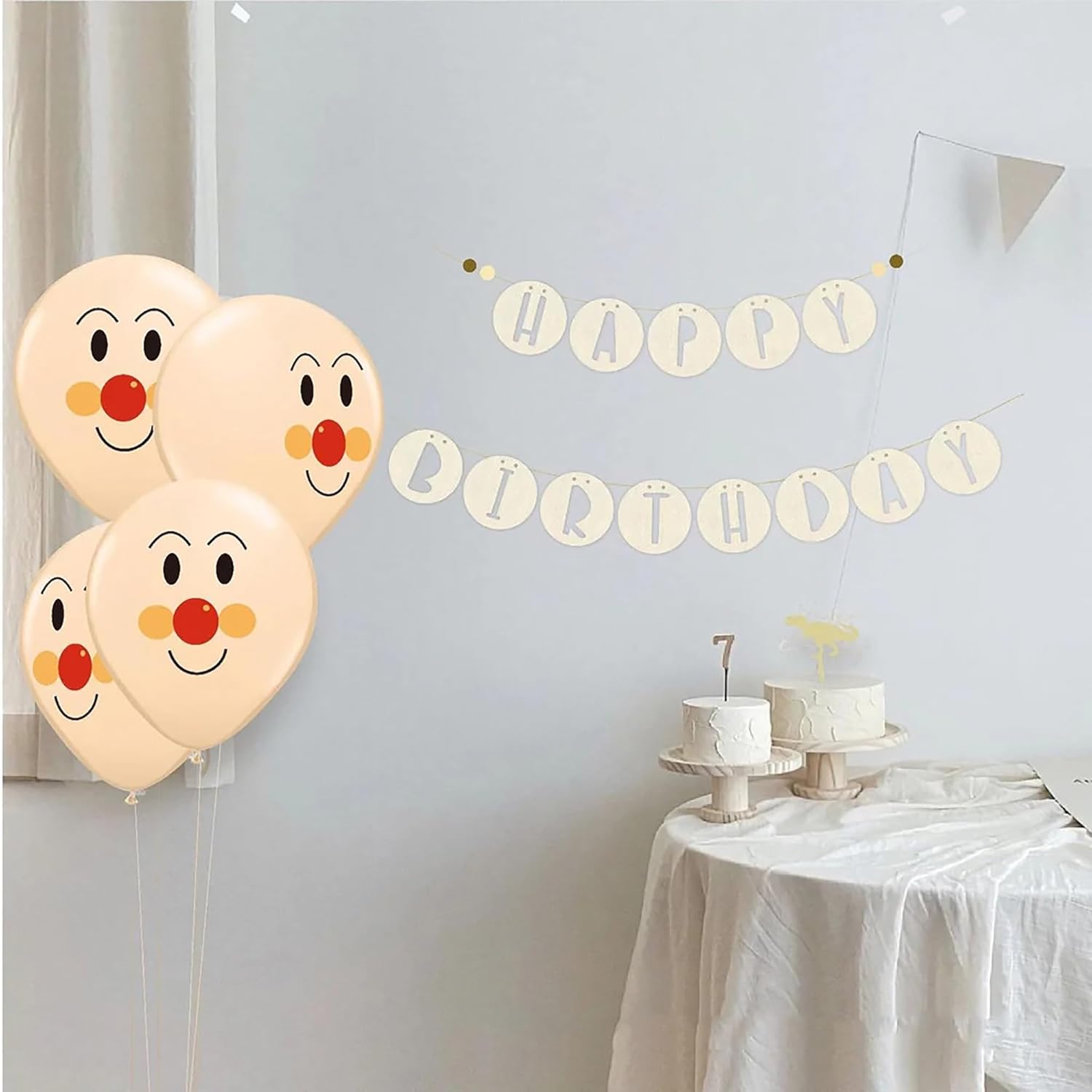 Four balloons with clown faces and a 'Happy Birthday' banner on a light gray wall.