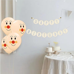 Four balloons with clown faces and a 'Happy Birthday' banner on a light gray wall.