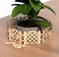 Wooden garden fence planter with a potted plant on a wooden surface