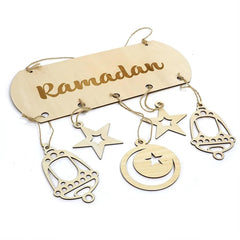 Decorative hanging sign with 'Ramadan' text and star, moon, and bell shapes on a white background.