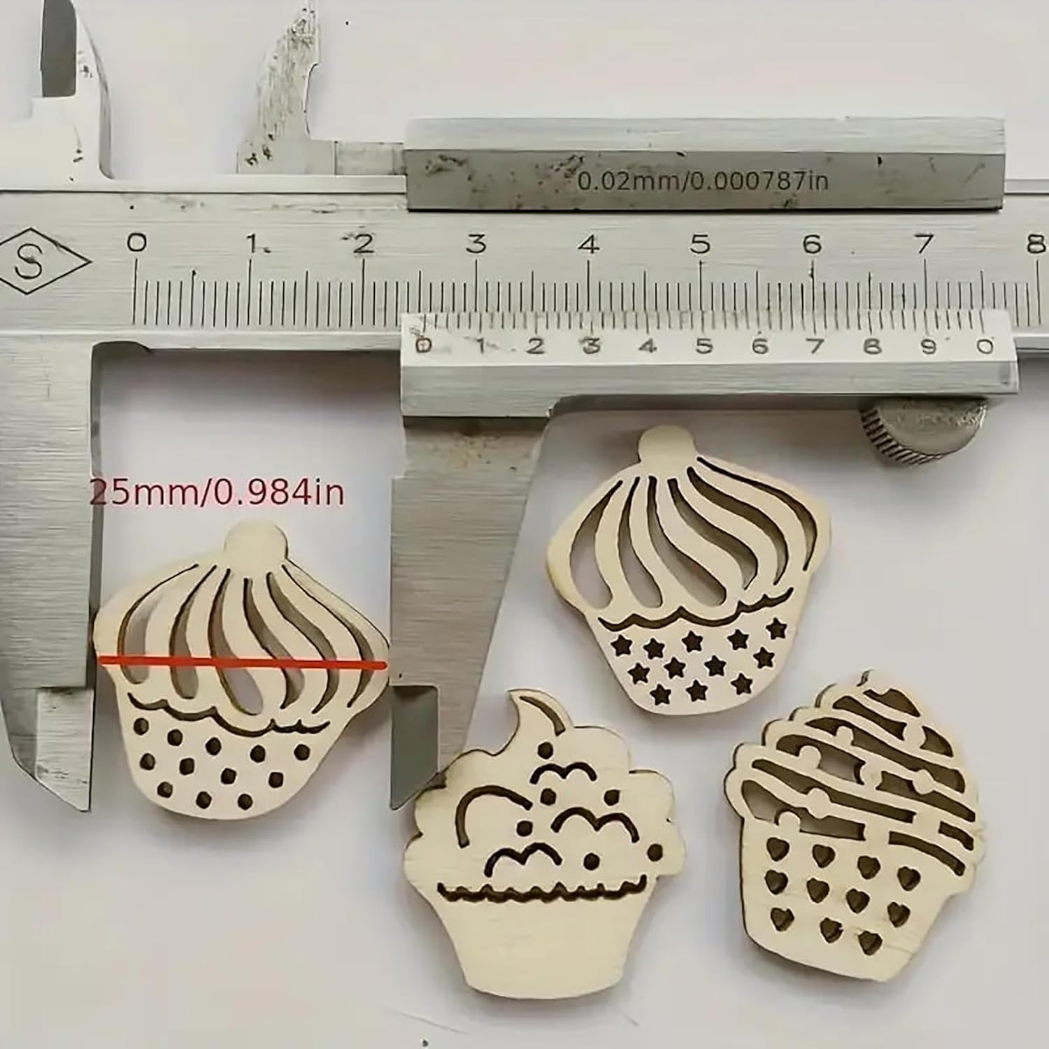 Wooden cupcake-shaped cutters with a caliper measuring their size on a white background