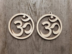 Two wooden om symbol earrings on a wooden background