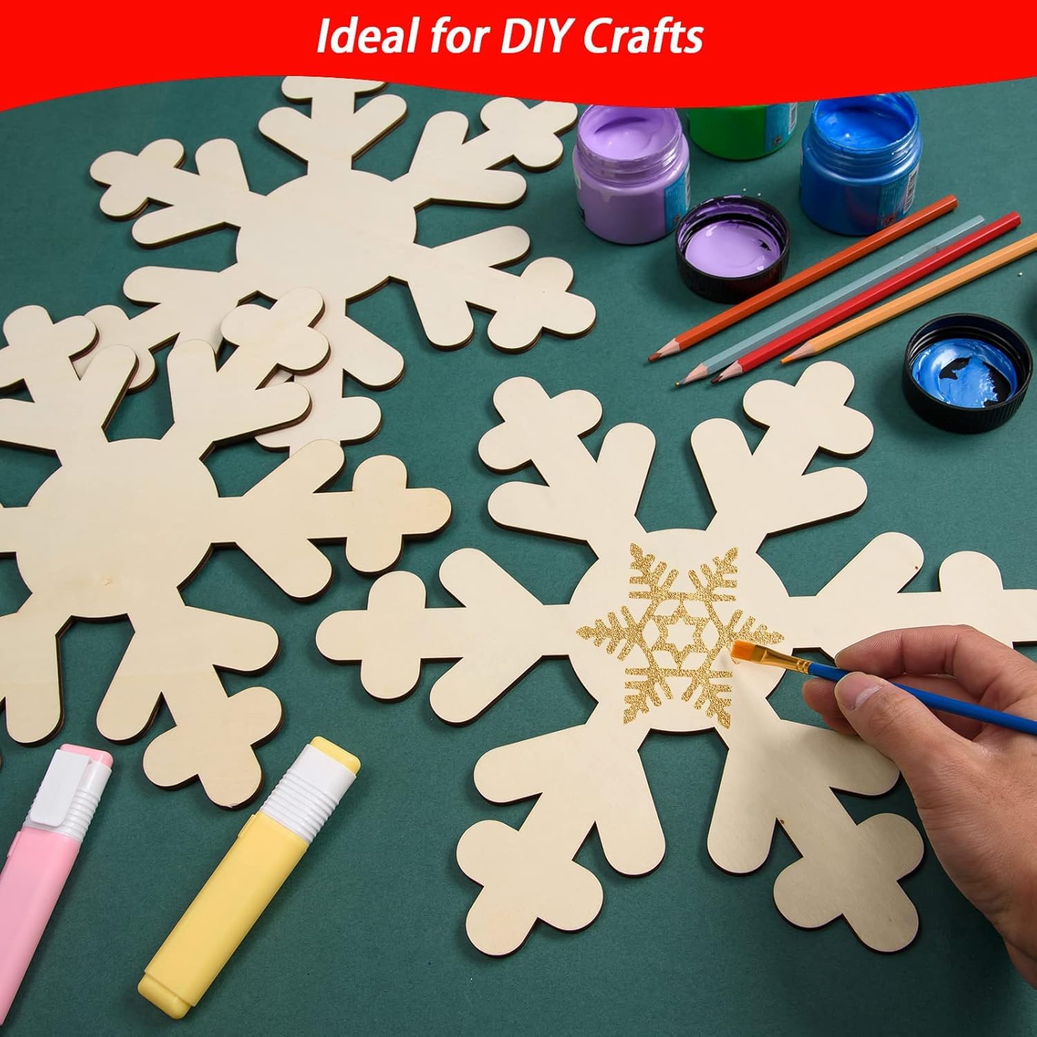 Wooden snowflakes with paint supplies on a green surface, ideal for DIY crafts.