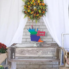 Decorative sign with colorful hand design and 'Ring Bearer' text on a wooden chest against a stone wall.